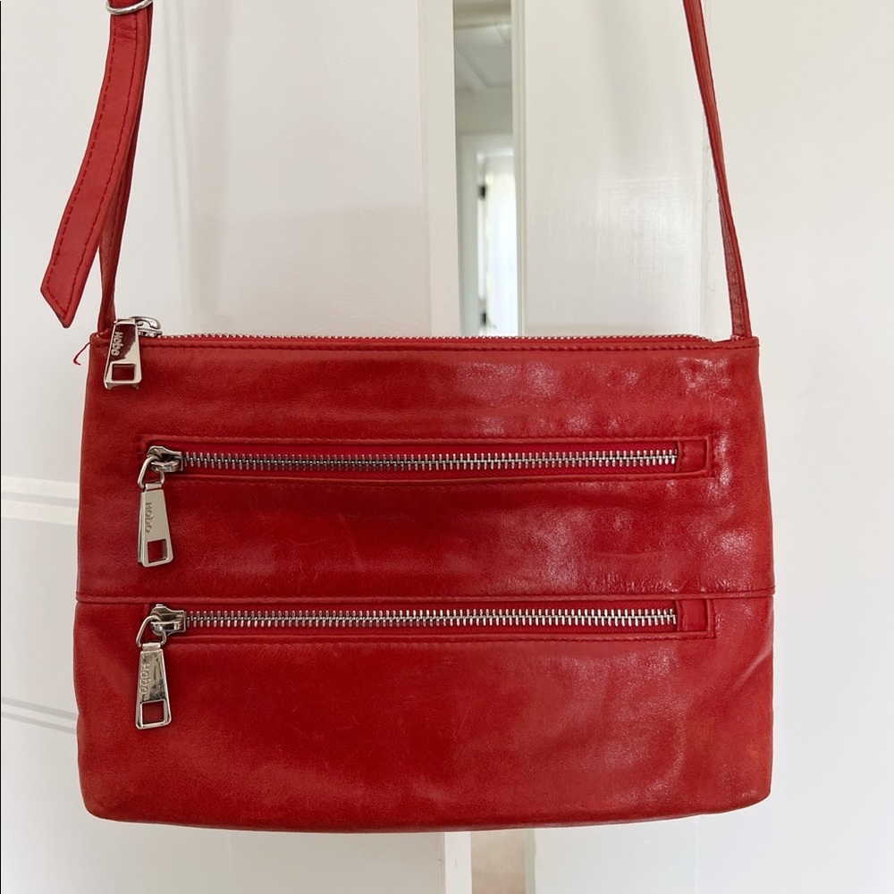 HOBO International Red leather crossbody purse with 3 zippers.